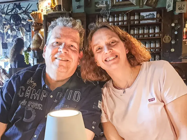 Ein Mann und eine Frau sitzen lächelnd an einem Tisch in einer gemütlichen Gaststube.