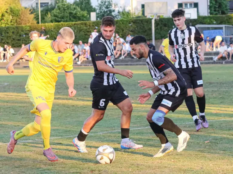 Spieler in Gelb und Schwarz-Weiß kämpfen auf einem Fußballfeld um den Ball.