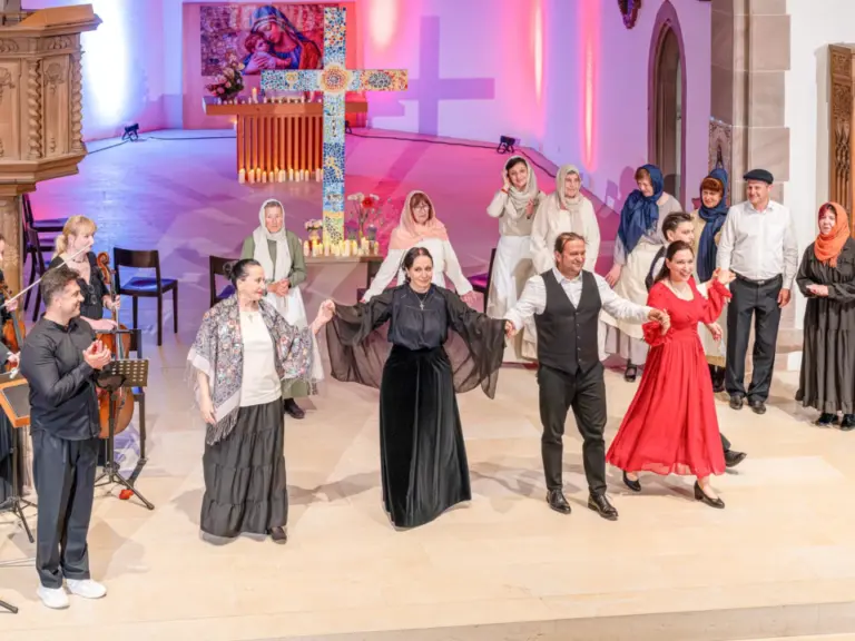 Sängerinnen und Sänger in historischen Kostümen sowie Musiker mit Geigen treten in einer Kirche auf.