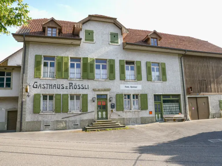 Altes verputztes Gasthaus mit grünen Fensterläden und der Aufschrift „Gasthaus z Rössli“.