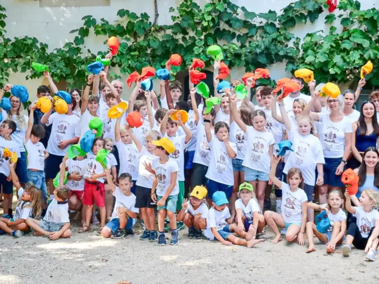 Grosse Gruppe von Kindern und Betreuenden posiert vor einem Haus, viele strecken bunte Wasserpistolen in die Luft.