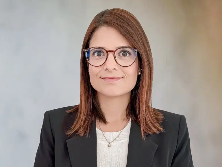 Eine Frau mit brauner Brille und schulterlangen Haaren im dunklen Blazer blickt in die Kamera.