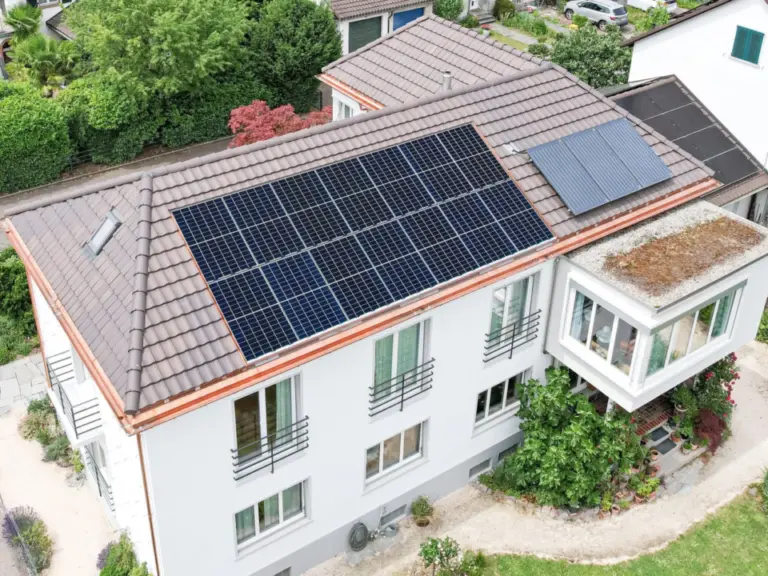 Luftaufnahme eines Hauses mit Ziegeldach, auf dem grossflächig Solarmodule montiert sind.