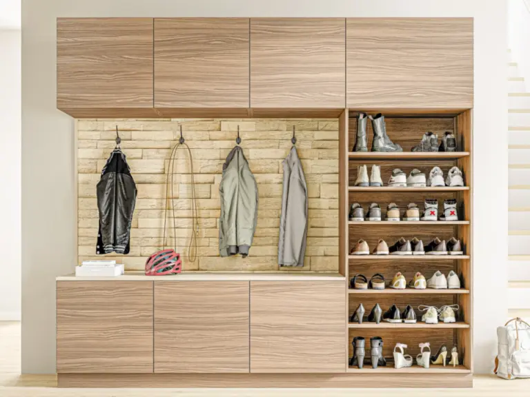 Garderobenschrank mit Hängefächern für Jacken, Schuhregal und Hakenleiste vor Steinwand.