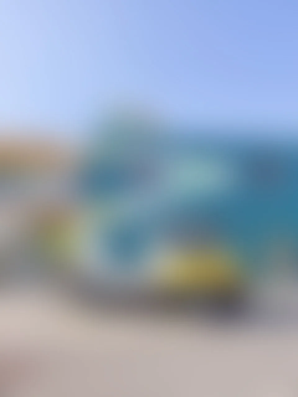 Unscharfes, verwischtes Bild mit türkisen, gelben und blauen Farbflächen, keine erkennbaren Details.