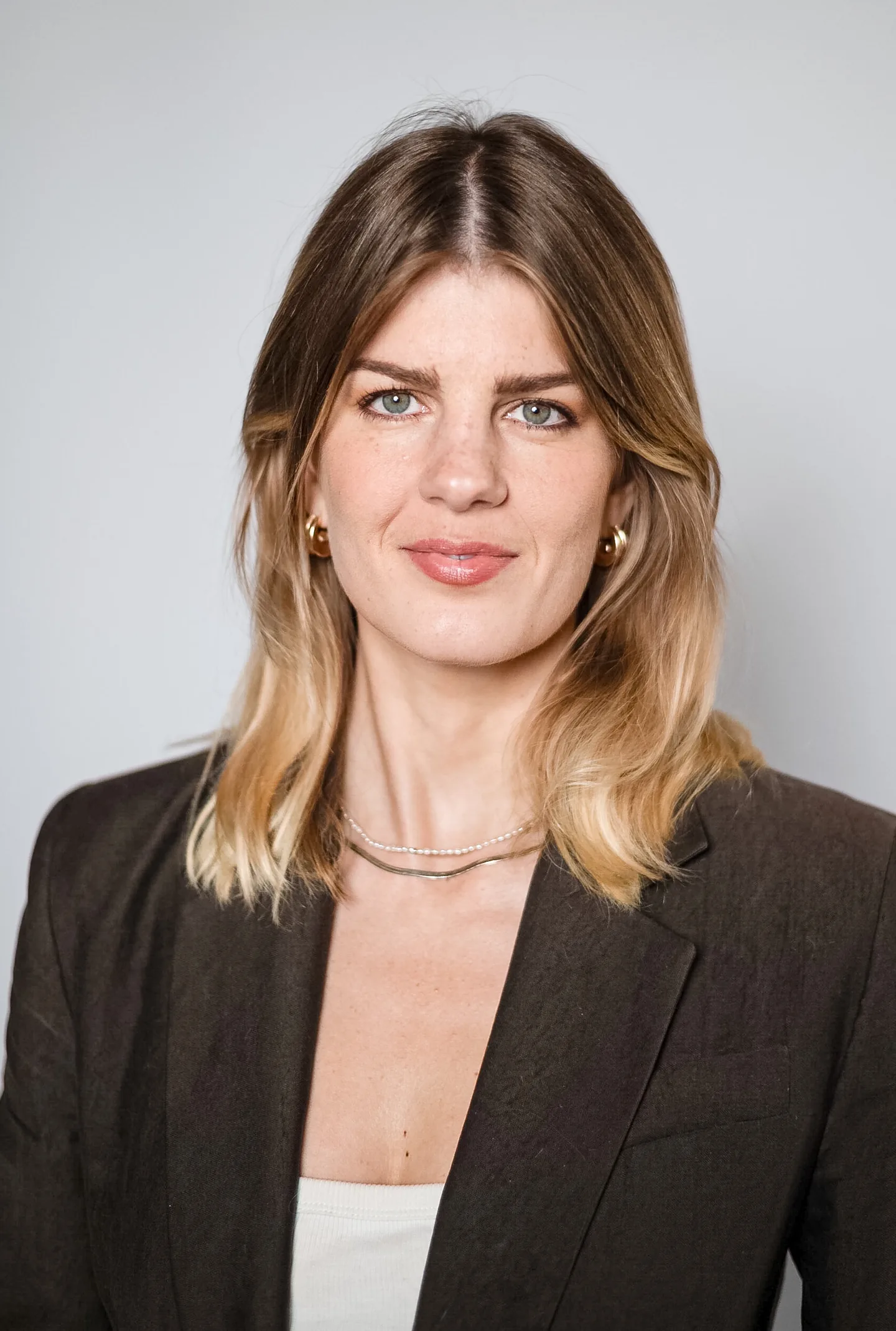 Eine Frau mit schulterlangen blonden Haaren blickt in die Kamera, sie trägt ein dunkles Sakko.