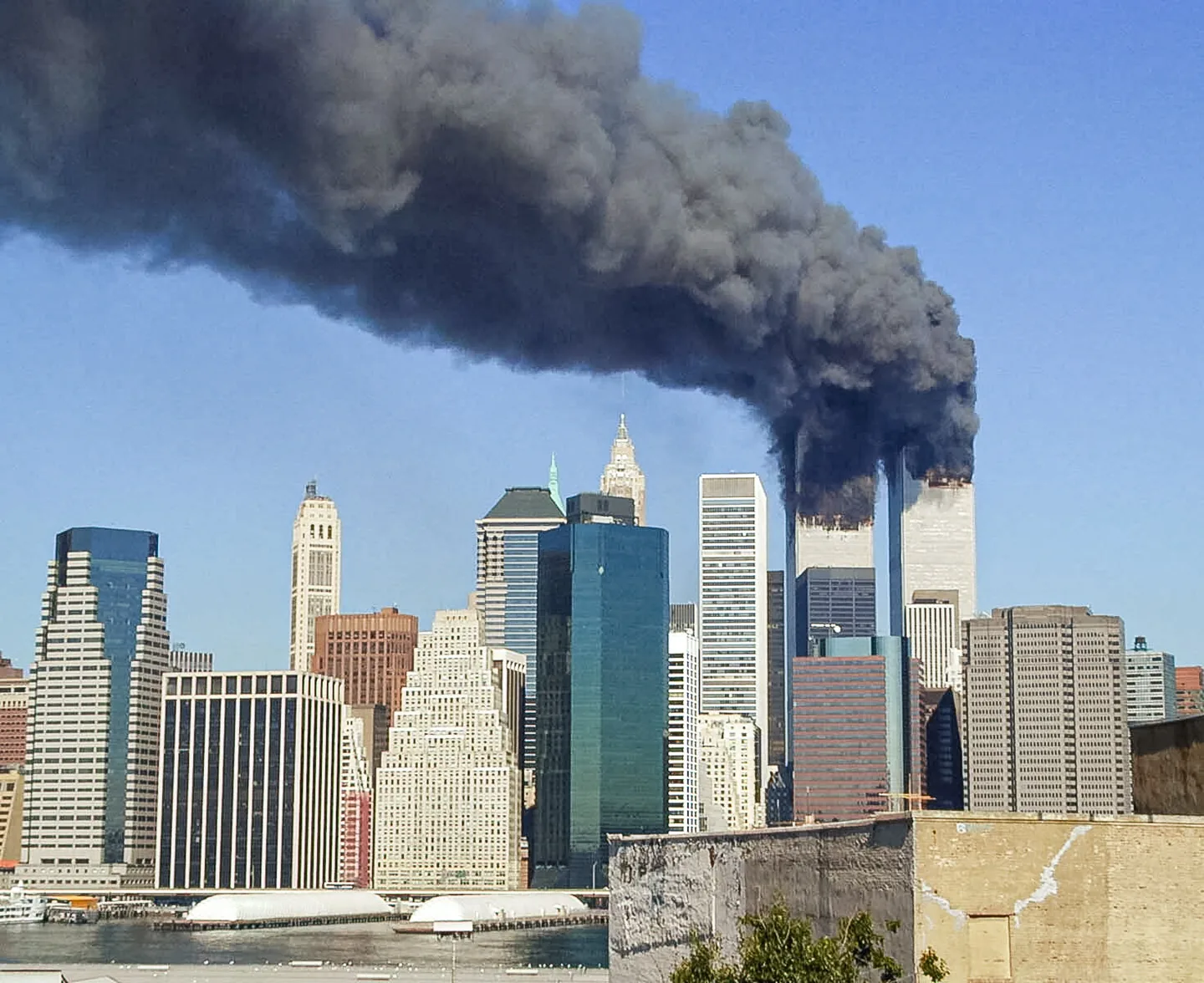 Dichte schwarze Rauchwolke steigt aus einem Hochhaus über der Skyline von Manhattan auf.