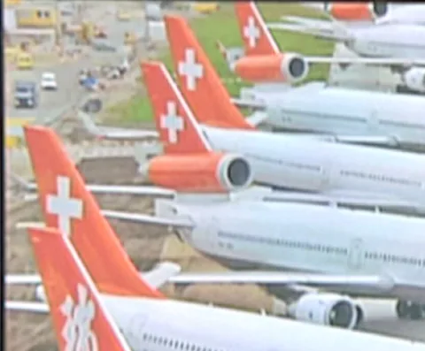 Fernsehbildschirm zeigt mehrere geparkte Swissair-Flugzeuge mit Schweizer Kreuz auf dem Leitwerk.