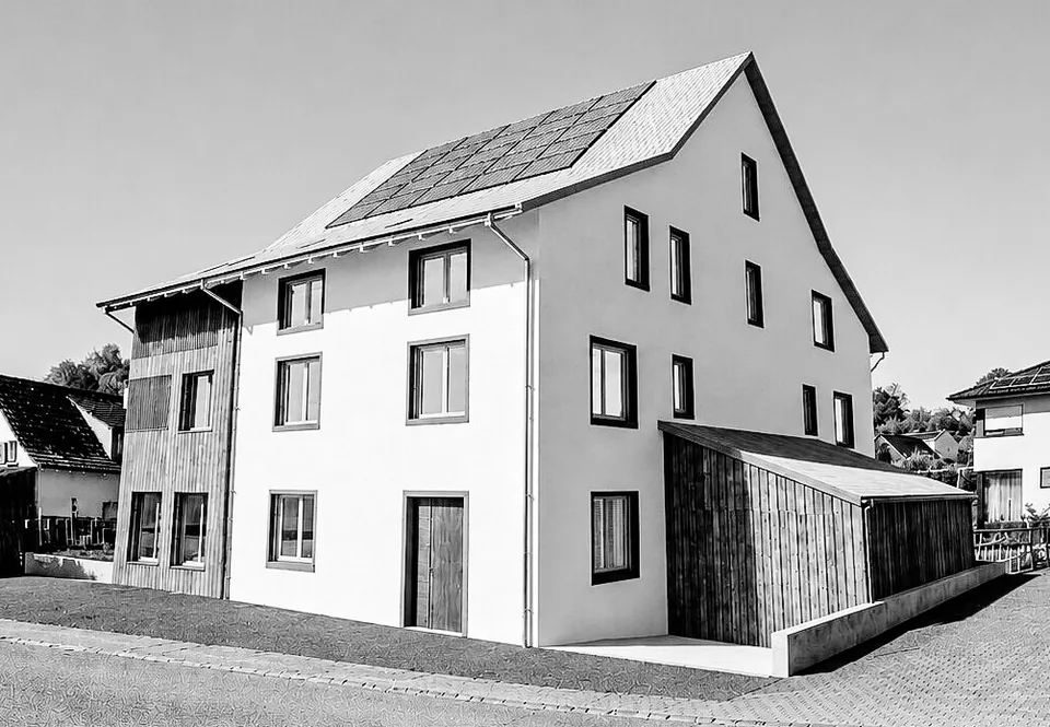 Schwarz-weisses Foto eines modernen Wohnhauses mit Satteldach und Solarpanels in einer Wohnstrasse.
