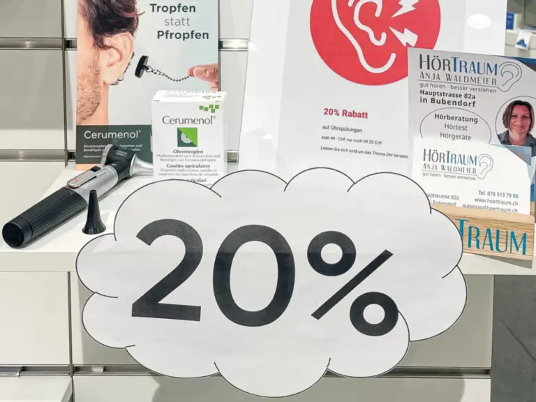Ein Aufsteller mit Wolkenform und Aufschrift „20%“ vor einer Apothekentheke mit Ohrpflegeprodukten und Plakaten.