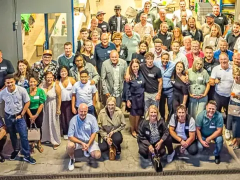 Grosse Gruppe von Menschen posiert vor dem Gebäude eines Instituts für ein gemeinsames Foto.