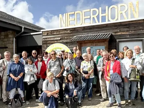 Eine grosse Gruppe posiert für ein Gruppenfoto vor der Bergstation Niederhorn.